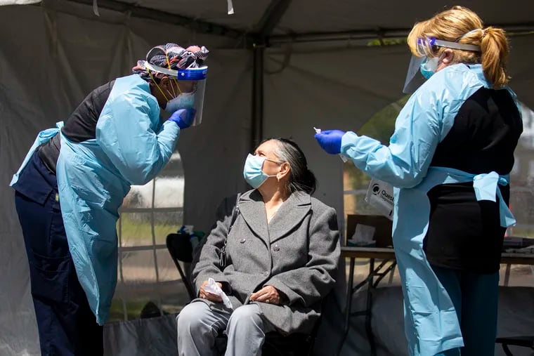Tijuana Johnson, LPN at Cooper University Health Care, instructs a woman to reveal her nose to conduct the test for the coronavirus at a testing site in Dudley Grange Park in Camden on Tuesday.