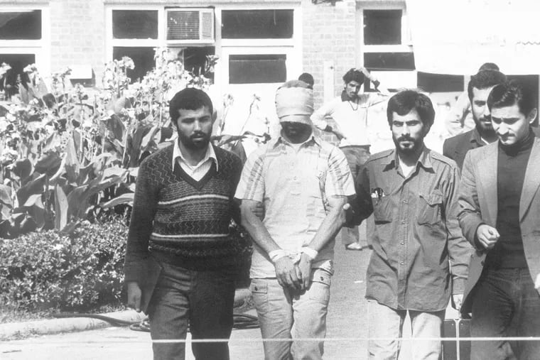 One of the hostages held at the U.S. Embassy in Tehran is shown to the crowd by Iranian students in early November 1979. At home, citizens rallied behind President Jimmy Carter.