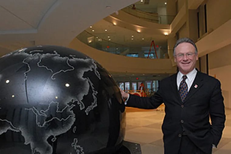 M. Moshe Porat, dean of Temple's Fox School of Business and School of Tourism and Hospitality Management, with a 6,400-pound granite globe that floats on a jet of water in the building's atrium.