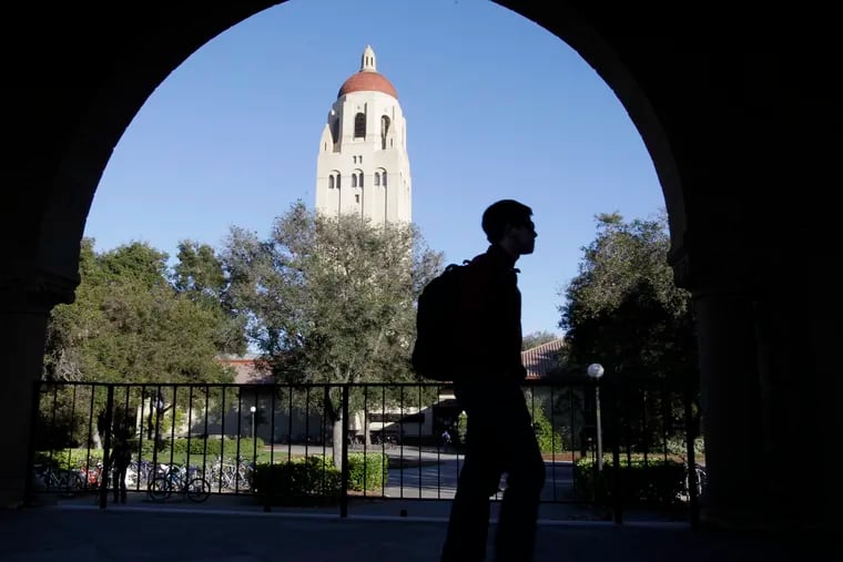 In this Feb. 15, 2012, file photo, a Stanford University student walks in front of Hoover Tower on the Stanford campus in Palo Alto, Calif. Federal authorities have charged college coaches and others in a sweeping admissions bribery case in federal court. The racketeering conspiracy charges were unsealed Tuesday, March 12, 2019, against coaches at schools including Stanford, Wake Forest, Georgetown, the University of Southern California and the University of Southern California, and UCLA.  (AP Photo/Paul Sakuma, File)