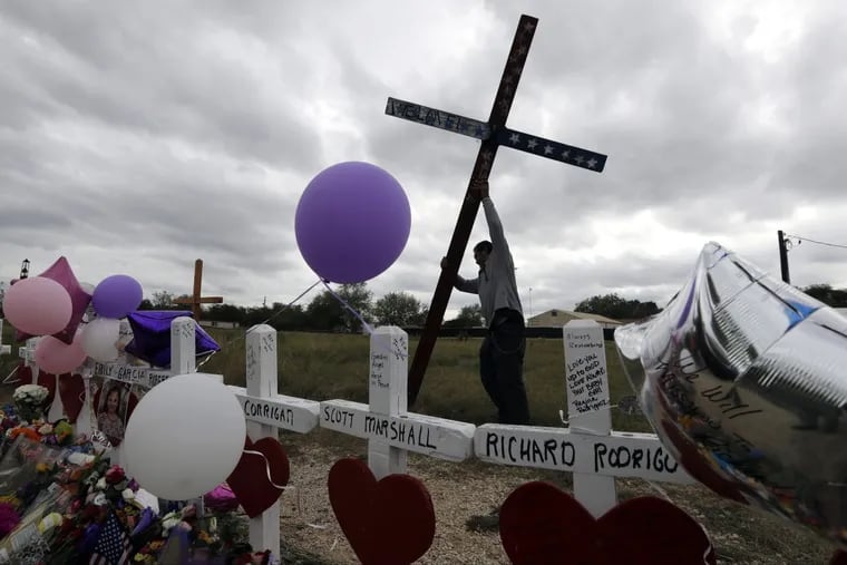 Miguel Zamora stands a cross for the victims of the Sutherland Springs First Baptist Church shooting at a makeshift memorial, Saturday, Nov. 11, 2017, in Sutherland Springs, Texas.