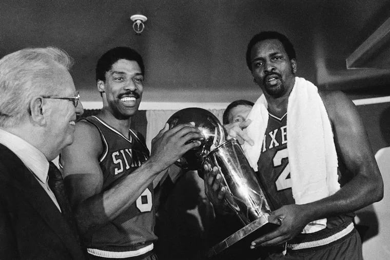 The Sixers' Julius Erving, left, and Moses Malone, right, hold the trophy after defeating the Lakers in the 1983 NBA Finals.
