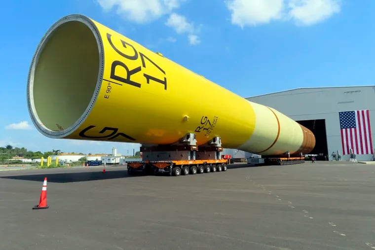 A huge foundation for an offshore wind turbine, called a monopile, sits atop wheeled movers in Paulsboro.