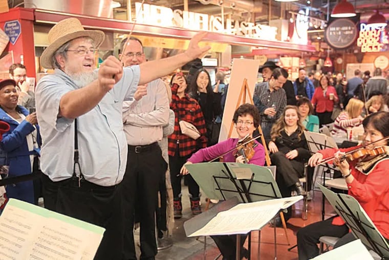 Moses Smucker, an Amish vendor at the Reading Terminal Market appears to be moved by the music as he conducts the string ensemble in Mozart's "Eine Kliene Nachtmusik" as a guest conductor on Monday afyernnon. A dozen Philadelphia Orchestra string players do a lunchtime pop-up concert in the heart of the Reading Terminal Market. 03/09/2015 ( Michael Bryant / Staff Photographer )