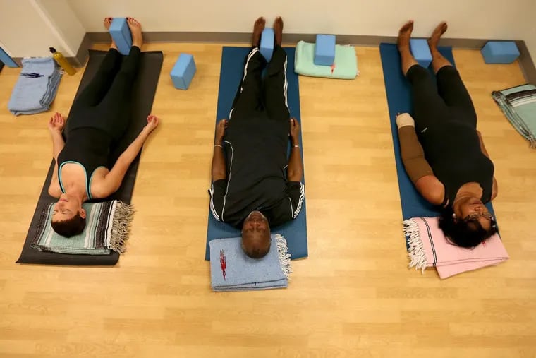 Jennifer Hook, 60, of West Philadelphia, Frank Garnes, 66, of Southwest Philadelphia, and Charmette Jackson, 71, left to right, participate in a yoga class held at the Hospital of the University of Pennsylvania. DAVID MAIALETTI / Staff Photographer