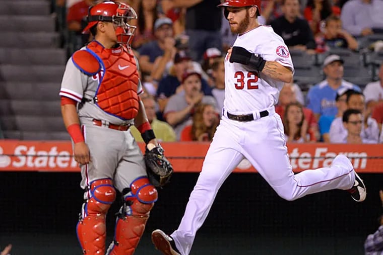 Josh Hamilton, right, scores on a single by Howie Kendrick as Philadelphia Phillies catcher Carlos Ruiz looks on during the sixth inning of a baseball game, Wednesday, Aug. 13, 2014, in Anaheim, Calif. (Mark J. Terrill/AP)