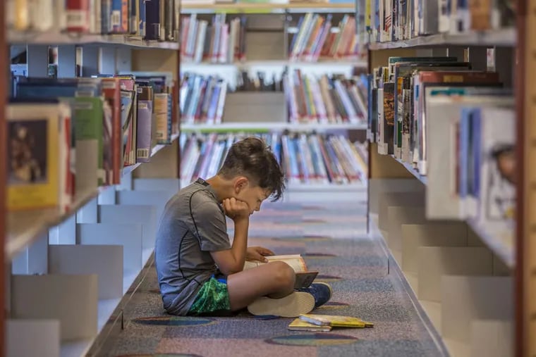 Judah Niv, 8, sits on the floor of the second floor children&#039;s book section of the Cherry Hill Public Library.