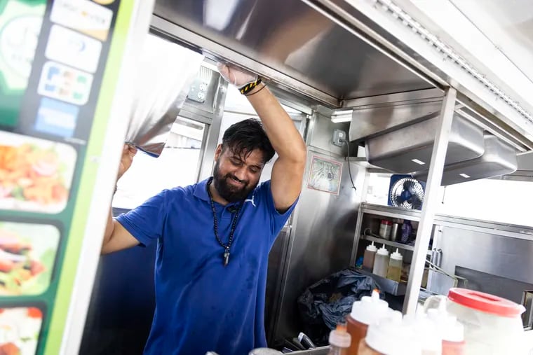 A small fan whirrs in the background as Fawad Khan, of South Philly, works over a hot griddle in his food cart at 21st and Washington Streets on Thursday. It's a hot business.