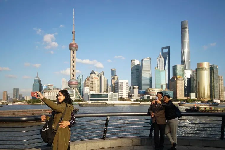 In this Nov. 12, 2020, file photo, people take selfies of the Pudong skyline as they stand on the Bund in Shanghai, China.