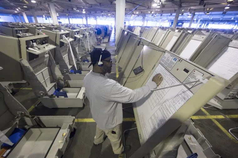 A technician prepares Philadelphia voting machines in 2016 that have no paper trail to detect fraud and are vulnerable to hacking, experts say.