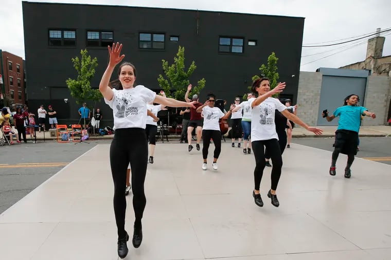 Members of the Philadelphia Community Tap Project tap dance on a stage in the middle of the street during National Tap Dance Day in Brewerytown Saturday afternoon.