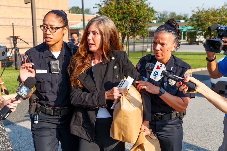 Former Pennsylvania Attorney General Kathleen Kane, center, makes her way through the media to a waiting SUV with the help of two Montgomery County Corrections officers after her release from the Montgomery County Corrections facility in Eagleville, PA on July 31, 2019.