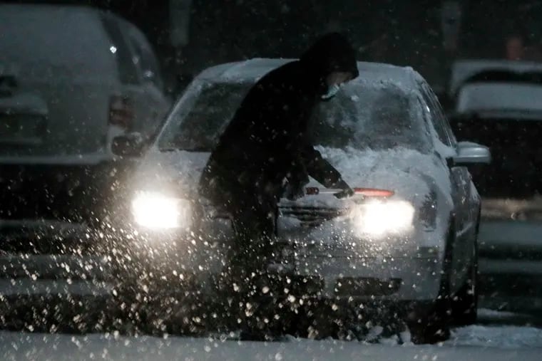 A person brushes the snow off their car in the WalMart parking lot in Williamstown, N.J. on Jan. 31, 2021.