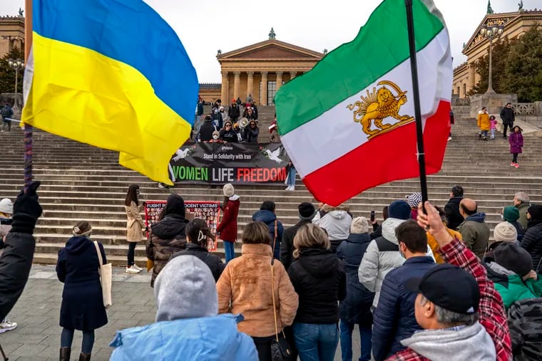 Montreh Tavakkoli, co-founder of Philly Iran, addresses members of the Philadelphia Iranian community and supporters during a protest rally on the steps of the Museum of Art Sunday, saying the names of the victims of Ukrainian Flight PS752 shot down by the Islamic Revolutionary Guard Corps in 2020. The flags are of Ukraine (left) and pre-revolutionary Iran.