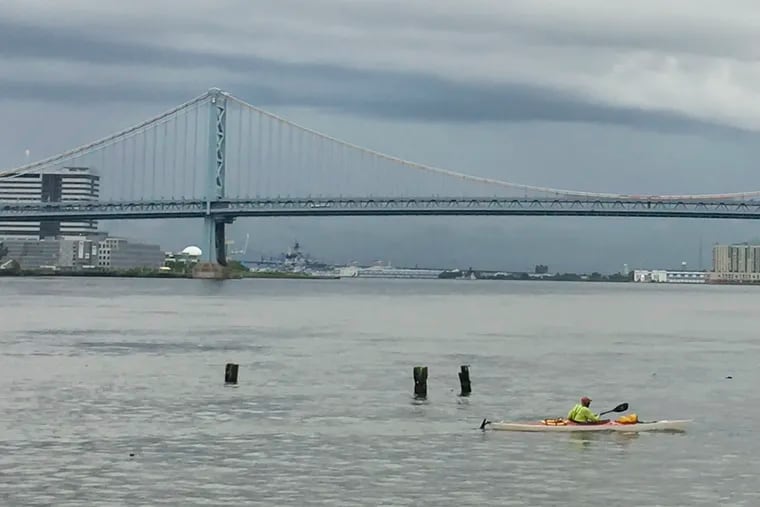 Kayaks along the Delaware River by the Ben Franklin Bridge as dark clouds being to roll in during a flash flood watch in September.