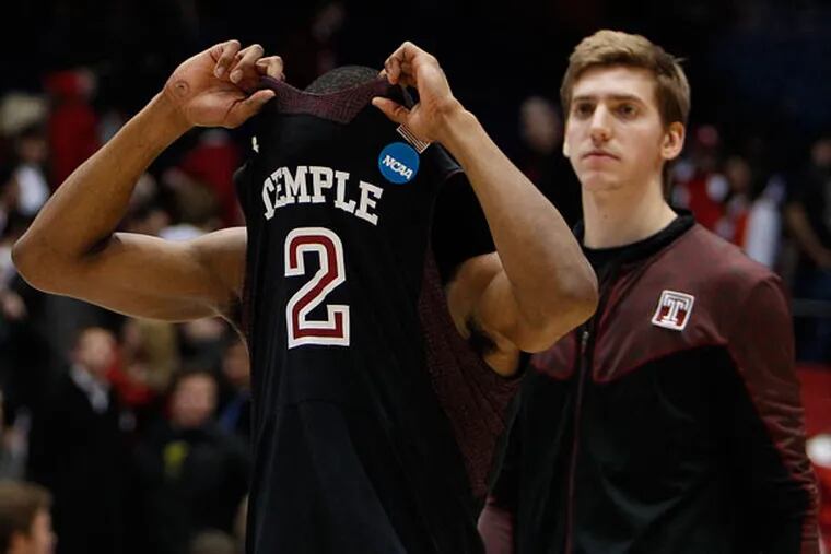 Temple's Will Cummings (left) covers his face with his jersey as he and his teammates walk off the court. (David Maialetti/Staff Photographer)