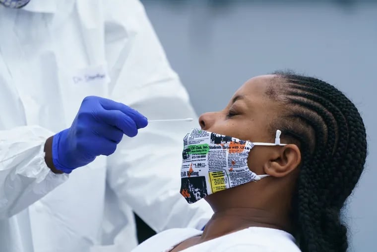 Tiffany Roberts-Williams gives a respiratory sample for coronavirus testing at a site run by the Black Doctors COVID19 Consortium, at the Global Leadership Academy in West Philadelphia in June.