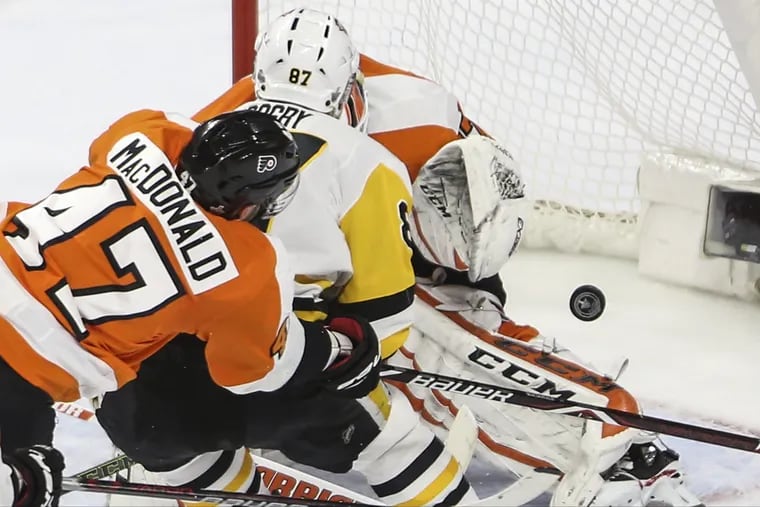 Flyers defenseman Andrew MacDonald battles Pittsburgh's Sidney Crosby in front of the net during last season's playoffs as goalie Brian Elliott makes the save.