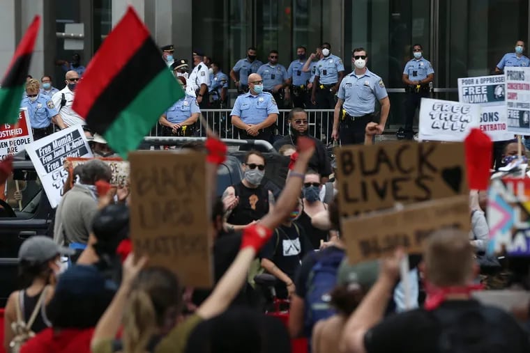 Police officers guard the Municipal Services Building as hundreds protest racism and police violence in Center City Philadelphia on July 4, 2020. Racist policing patterns have been a central theme of protests in Philadelphia.
