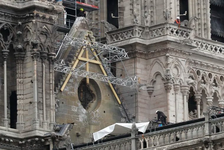 Workers install tarps at Notre Dame cathedral,Tuesday, April 23, 2019 in Paris. The man in charge of the restoration of the fire-ravaged Notre Dame cathedral says he has appointed professional mountain climbers to install temporary tarps over the building to offset potential rain damage.