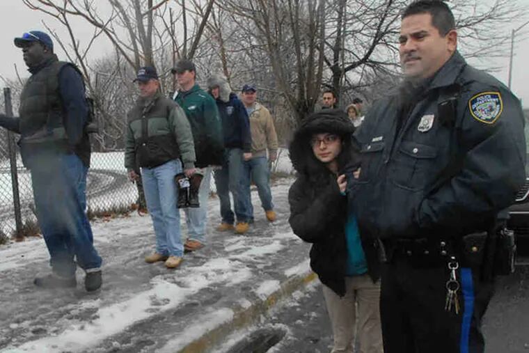 FILE: Jan. 2011: Camden Police Officer Raymond Rusi, who was laid off but was in uniform because he had to appear in court, watches with daughter Jaymilie, 11, as laid-off co-workers file past to place their boots in a symbolic row.