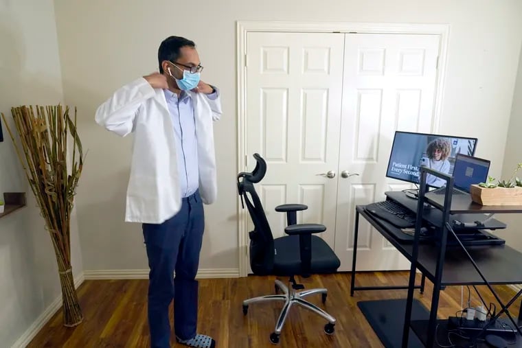 Medical director of Doctor on Demand Dr. Vibin Roy prepares to conduct an online visit with a patient from his work station at home, April 23, 2021, in Keller, Texas.  One Harvard Business School professor call remote work a win-win for employers and employees. (AP Photo/LM Otero, File)