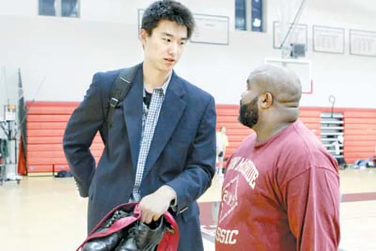 Tao Xu, a 6-foot-11 high school basketball player from China, chats with Charles Monroe, assistant basketball coach at Haverford School.