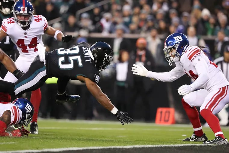 Eagles running back Boston Scott runs into the end zone for a first quarter touchdown against New York Giants cornerback Nick McCloud (right) on Sunday, January 8, 2023 in Philadelphia.