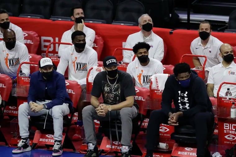Sixers guard Seth Curry, guard Ben Simmons and center Joel Embiid sit on the bench in street clothes as their teammates take on the the Orlando Magic in the third quarter on Sunday.