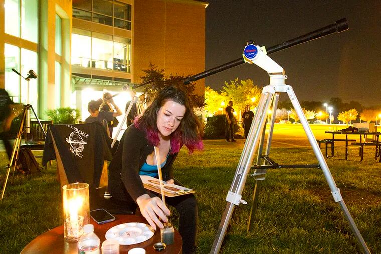 Heather Lentz paints pictures of the full moon by candlelight on May 4, 2015. ( CHARLES FOX / Staff Photographer )