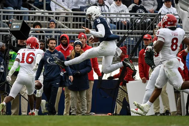 Penn State quarterback Christian Veilleux goes airborne on a keeper while trying to elude Rutgers defenders Tyshon Fogg (8) and Max Melton (16).