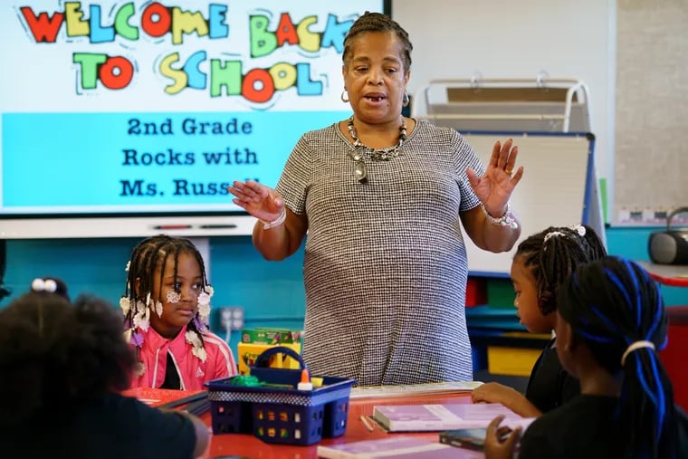 Second-grade Teacher Deborah Russell, center, instructs students Lilly Jane Johnson-Russell, left, and Jasmine Bryant, right, on the first day of school at Robert Morris Elementary in North Philadelphia on Sept. 3, 2019.