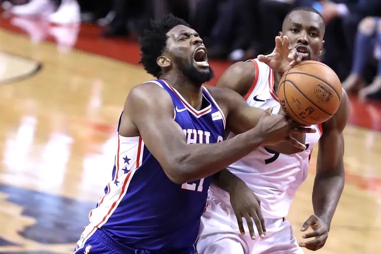 Joel Embiid, left, of the Sixers gets fouled by Serge Ibaka of the Raptors during the 2nd half of their NBA playoff game at the Scotiabank Arena in Toronto on April 29, 2019.