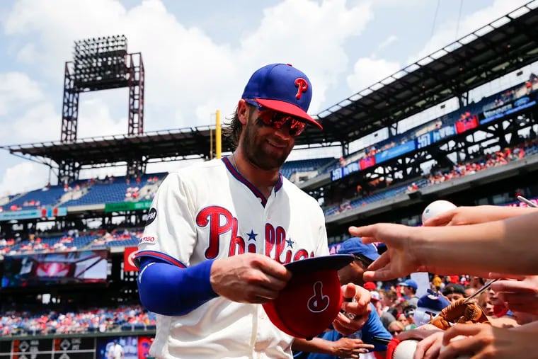 Phillies right fielder Bryce Harper signs his autograph for fans before the Phillies played the San Diego Padres on Sunday in Philadelphia.