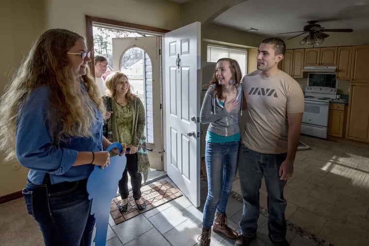Retired U.S. Air Force Staff Sergeant Eric Began, 32, and his wife Sheryl, 25, walk into their new home in Sicklerville after being given the keys to the mortgage-free house by Operation Home Front in conjunction with J.P. Morgan Chase.  At left is Madison Dillon, Operation Homefront housing caseworker. Others in the background are family members of the couple. Began served in both Afghanistan and Iraq and left the military in 2009.