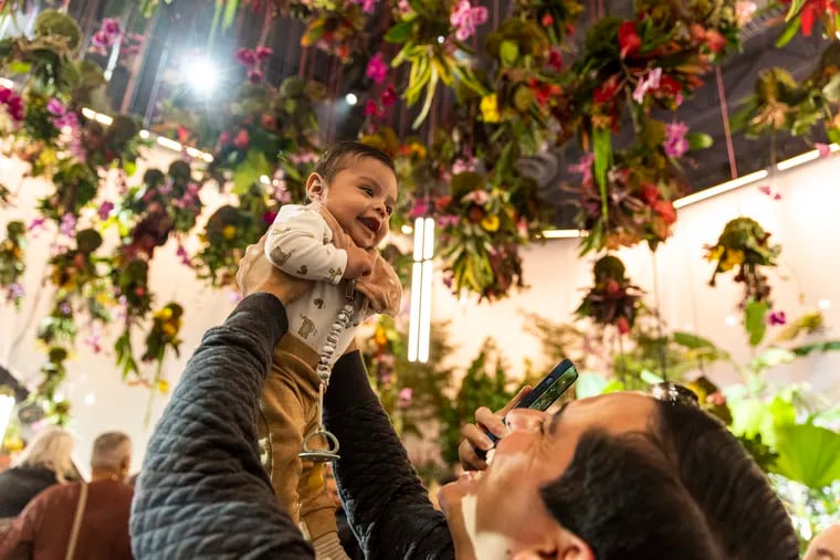 Leo Sanchez, of Raritan, N.J., holds up his son, Luca Sanchez, 4 months, inside the entrance of last year's the Garden Electric Flower Show at the Convention Center.