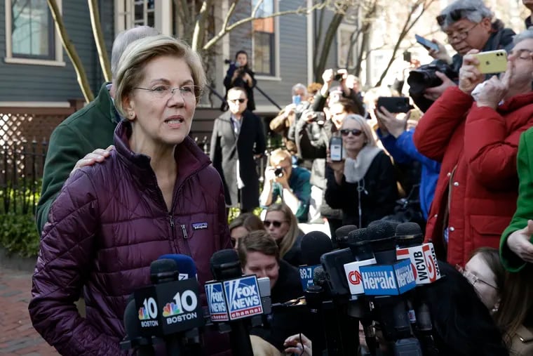 Sen. Elizabeth Warren, D-Mass., with her husband Bruce Mann's hand on her shoulder, speaks to the media outside her home, Thursday, March 5, 2020, in Cambridge, Mass., after she dropped out of the Democratic presidential race.