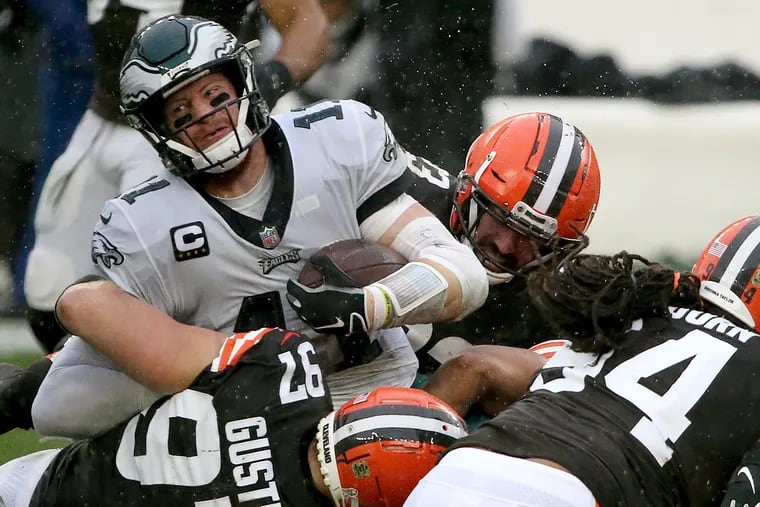 Eagles QB Carson Wentz (left) fights for extra yards on a run as he is tackled by a host of Browns defenders in Sunday's 22-17 loss.