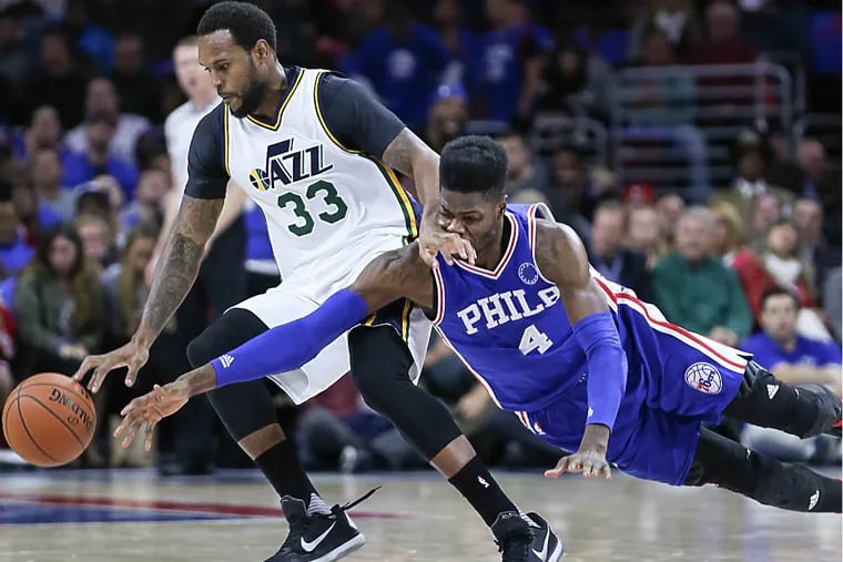 Nerlens Noel dives for a loose ball with Jazz's Trevor Booker during the 2nd quarter of Friday night's home opening blowout loss.