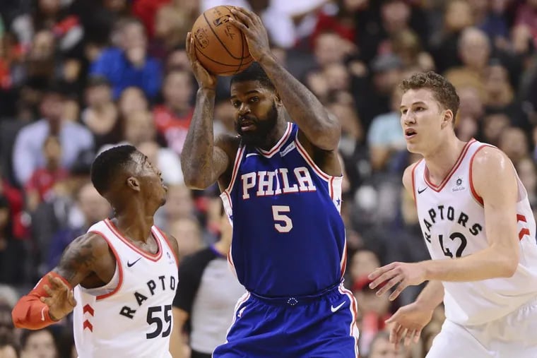 Sixers forward Amir Johnson (5) looks to pass the ball under pressure from Raptors guard Delon Wright (left) and center Jakob Poeltl during Saturday’s game in Toronto.