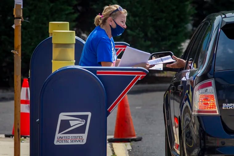 United State Post Office clerk Christine Tarducci passes a flyer to people as they drop off mail that reads "Defend Your Postal Service" during a rally in support of postal workers at the U.S Post Office in Northeast Philadelphia in August.