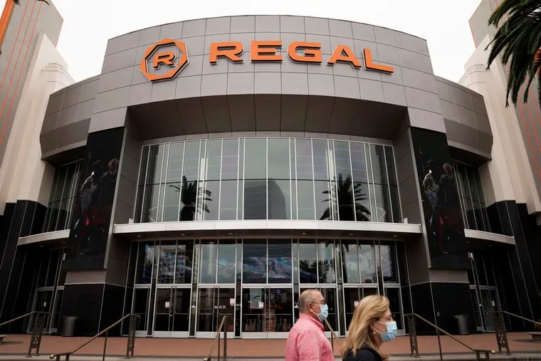 In this Sept. 8, 2020, file photo, two shoppers in face masks due to the coronavirus pandemic walk past a Regal movie theater in Irvine, Calif. Cineworld, which owns Regal Cinemas in the U.S., considers bankruptcy as movie-theater struggles continue.