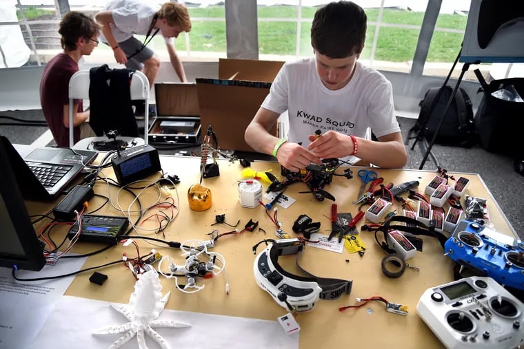 At Philly's first Maker Faire, Kevin Fallon (at table), Sam Weissman (rear, left) and Nolan Gelinas (rear, right) work on their drones as part of the Kwad Squad, a group of high school classmates and family friends formed to pursue their passion.