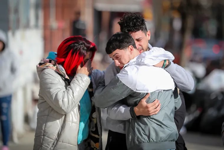 Family members of fallen Temple police officer Christopher Fitzgerald embrace at a makeshift memorial near 17th Street and Montgomery Avenue on Sunday.