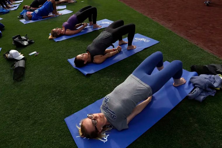 Kristyn Burtt, right, of Los Angeles, participates in a yoga class lead by Mia Togo from Yogaworks after the Dodgers game on May 17, 2015 at Dodger Stadium, in Los Angeles. The yoga class was 30 minutes long, and the field was filled with participants. (Francine Orr/ Los Angeles Times/TNS)