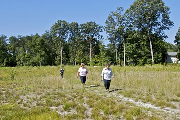 Neighbors, left to right, Alave Phifer, Mary Palumbi and Lisa Cowne walking along a trail in the proposed site of a $21 M, 11-acre army reserve training facility in Gloucester Township. ( John Costello / Staff Photographer )