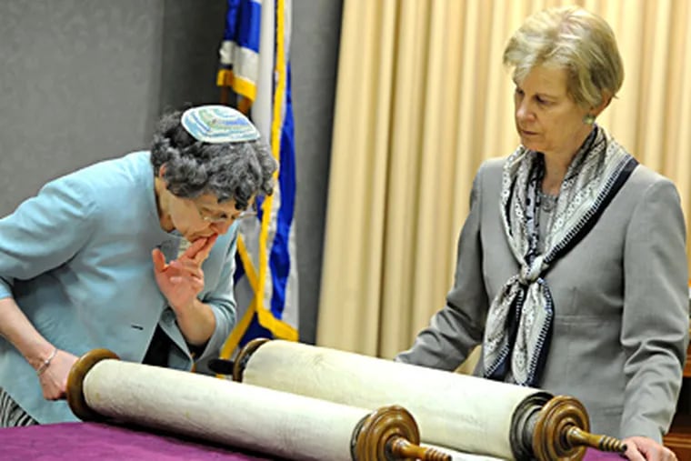 At Martins Run in Marple Township, Rabbi Meryl Crean reads from a 130-year-old Torah rescued from Czechoslovakia as Linda Sterthouse, the senior community's chief executive officer, observes. CLEM MURRAY / Staff Photographer