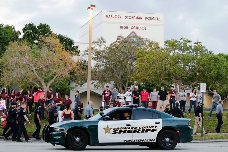 FILE - In this Feb. 28, 2018, file photo, a police car drives near Marjory Stoneman Douglas High School in Parkland, Fla., as students return to class for the first time since a former student opened fire there with an assault weapon. Republican Florida Gov. Ron DeSantis has signed a bill that will allow more classroom teachers to carry guns in school, a response to last year's mass shooting at the high school.