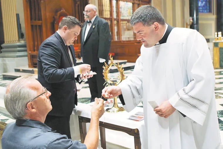 Father Fregory Gresko, chaplain of the St. John Paul II National Shrine, hands a necklace back to a parishioner after it was held against the relic. The relic consists of a vial of St. John Paul II's blood and was available for veneration at Cathedral Basilica of Saints Peter and Paul in Philadelphia. ( MICHAEL S. WIRTZ / Staff Photographer )