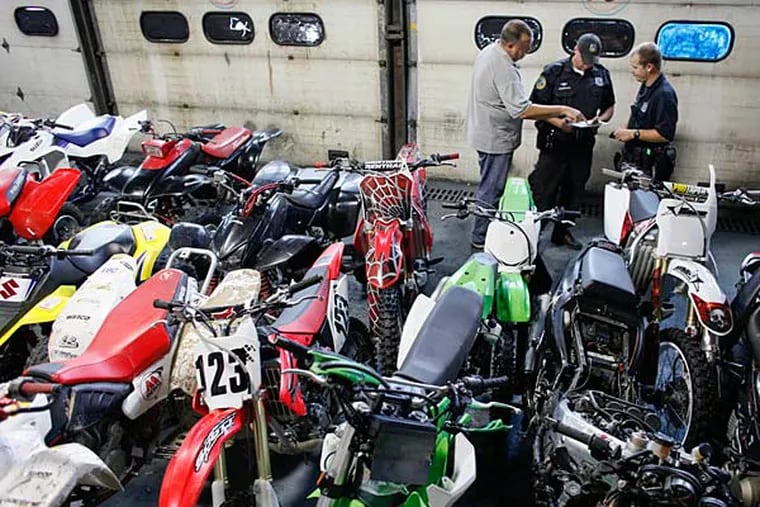 Police from the auto squad unit look over numerous ATVs and dirt bikes, Sunday Aug. 5, 2012, which were confiscated during a sting operation in the Kensington section of Philadelphia. (For the Inquirer and Daily News/ Joseph Kaczmarek)
